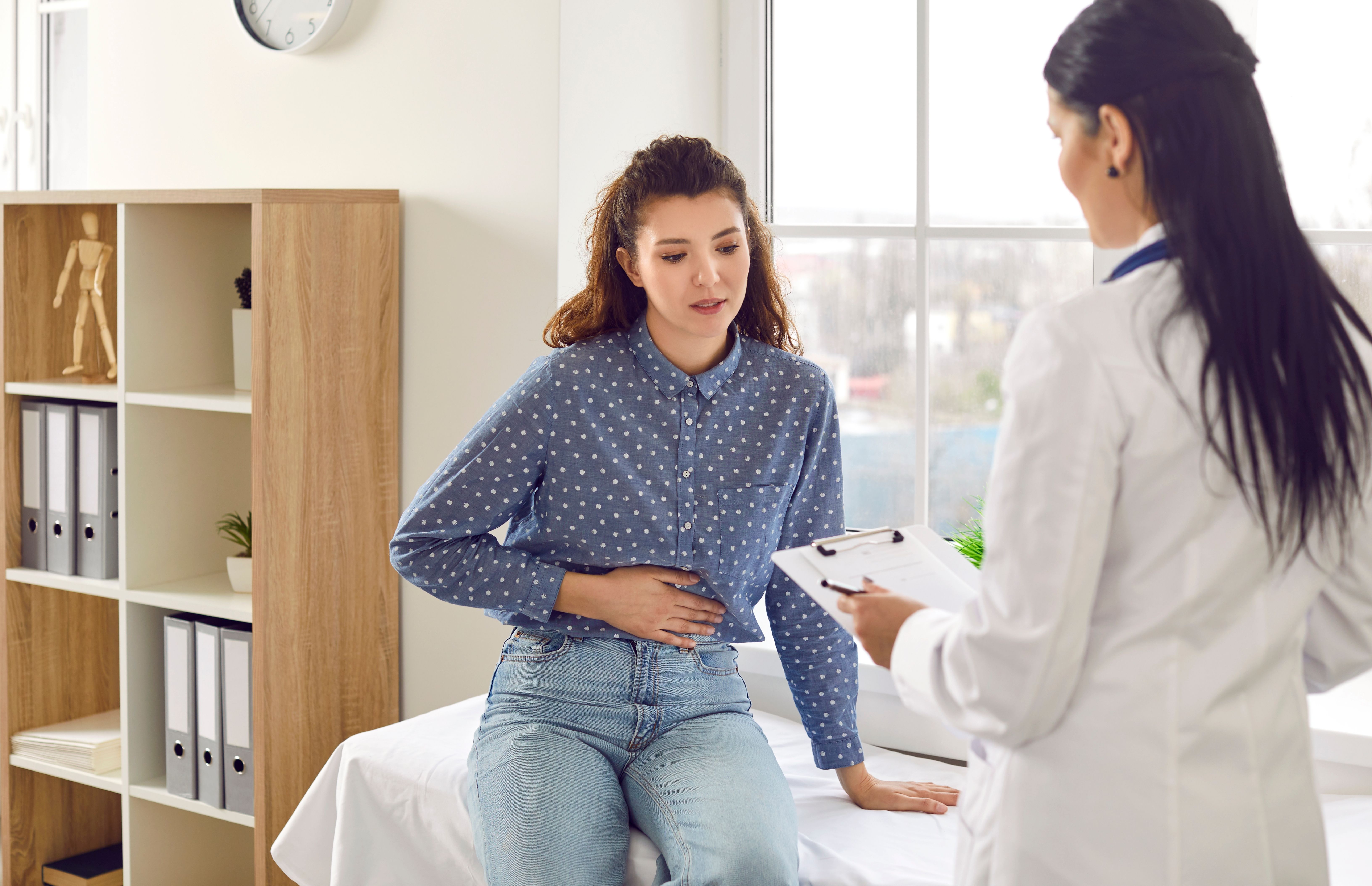 Woman describing stomach pain to a doctor in office.